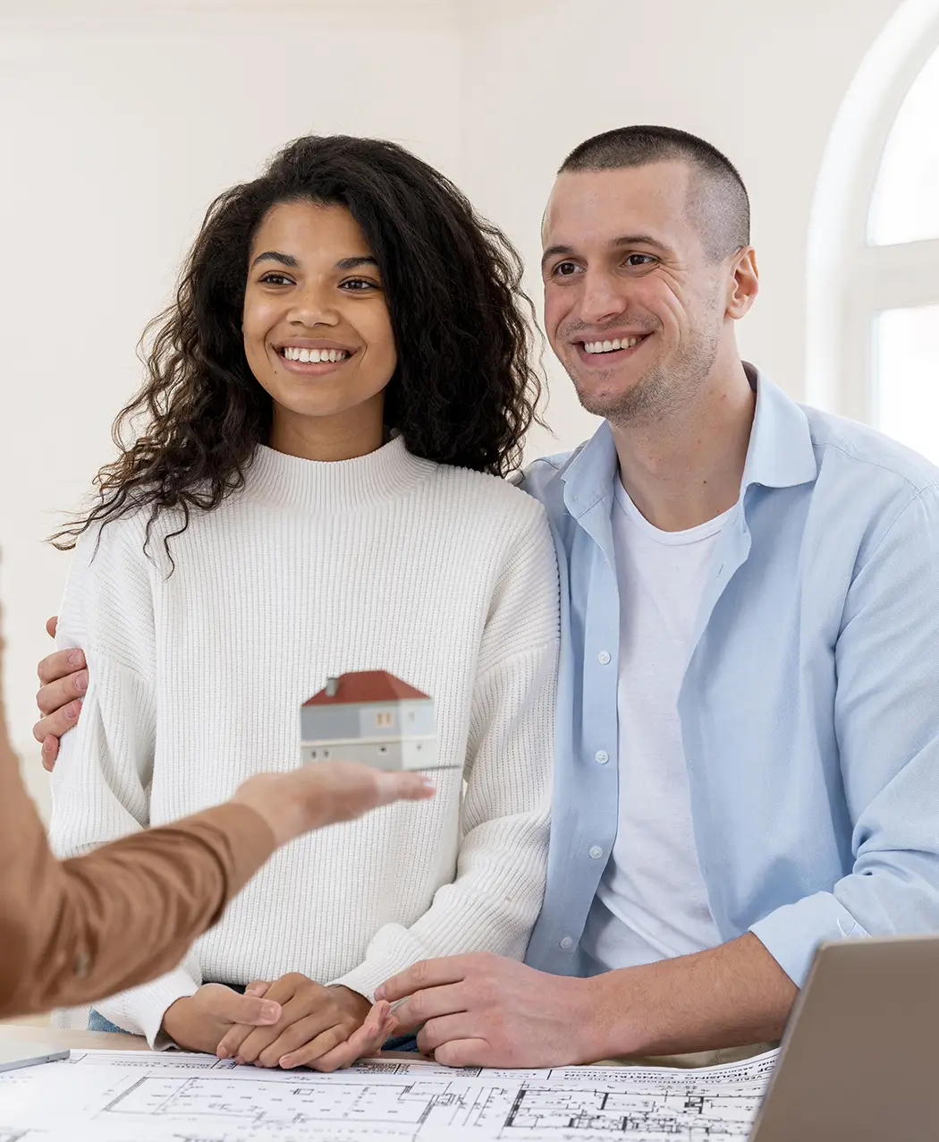 Smiling couple receiving a model house from their property adviser